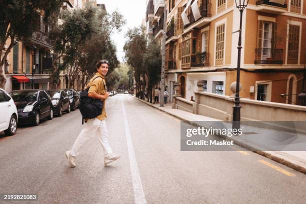 side view of male tourist crossing road in city - explorador imagens e fotografias de stock