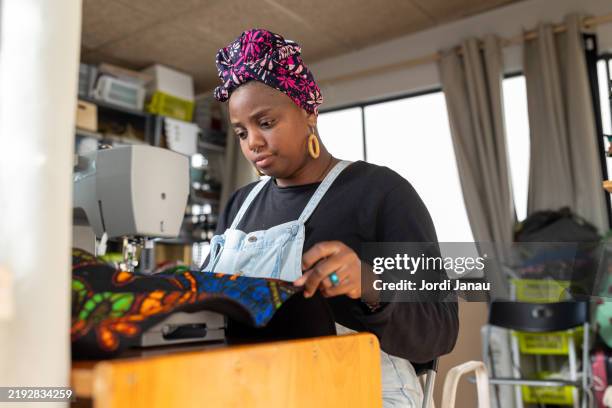 african clothing designer working on a sewing machine - schneiderin stock-fotos und bilder