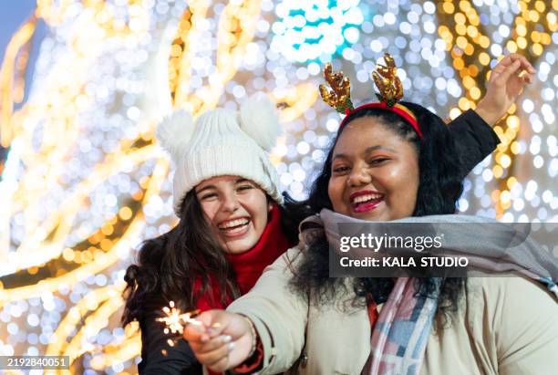 two friends celebrating christmas with sparkler and lights - espírito natalino imagens e fotografias de stock