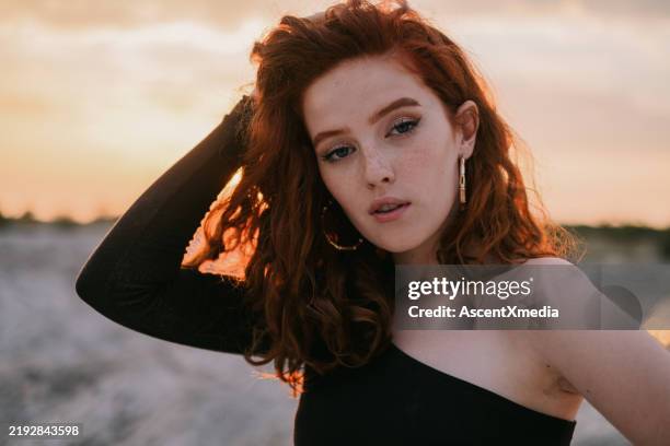 portrait of young woman posing on beach at golden hour - robe asymétrique photos et images de collection