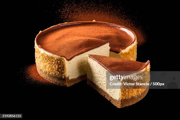 a photo of a slice of cheesecake with a chocolate cream topping,isolated on a black background - cheesecake stock pictures, royalty-free photos & images