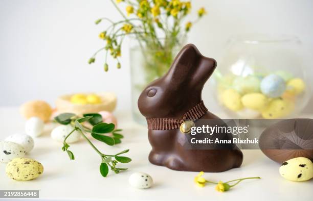 chocolate easter bunny and candies eggs on white table against white background - lots of rabbits stock pictures, royalty-free photos & images