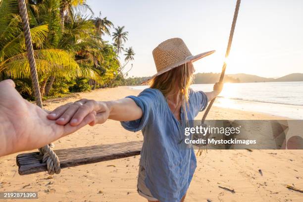 mujer en el columpio de la playa de la mano con su pareja - columpio de cuerda fotografías e imágenes de stock