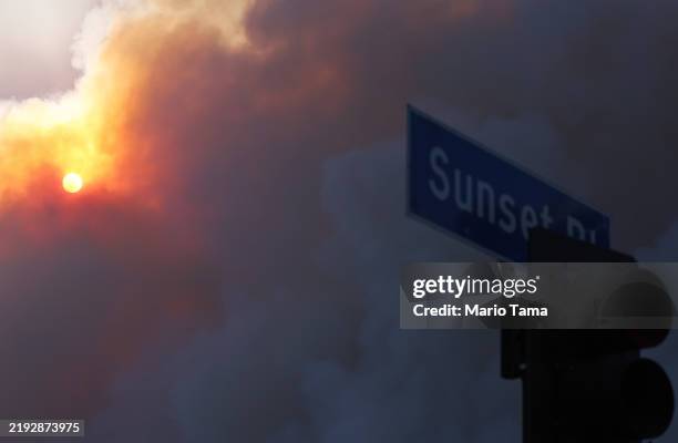 The Palisades Fire burns beyond a Sunset Boulevard street sign amid a powerful windstorm on January 7, 2025 in Pacific Palisades, California. The...