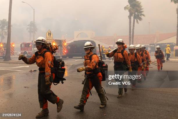 Firefighters work at the site of a brush fire pushed by gusting Santa Ana winds on January 7, 2025 in Pacific Palisades, Los Angeles, California. A...