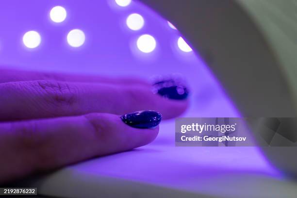 woman using uv light dryer - ultraviolet light stock pictures, royalty-free photos & images
