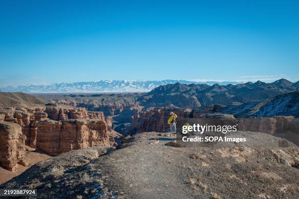 Tourists are seen gesturing against the background of Sharyn Canyon, or known Charyn Canyon, in Kazakhstan. The landlocked country is often battered...