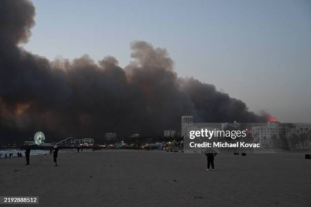 Smoke from the Palisades Fire fills the sky as seen from Santa Monica Beach, with the Santa Monica Pier and Ferris Wheel in the foreground on January...