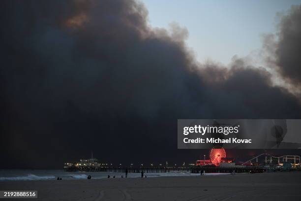 Smoke from the Palisades Fire fills the sky as seen from Santa Monica Beach, with the Santa Monica Pier and Ferris Wheel in the foreground on January...