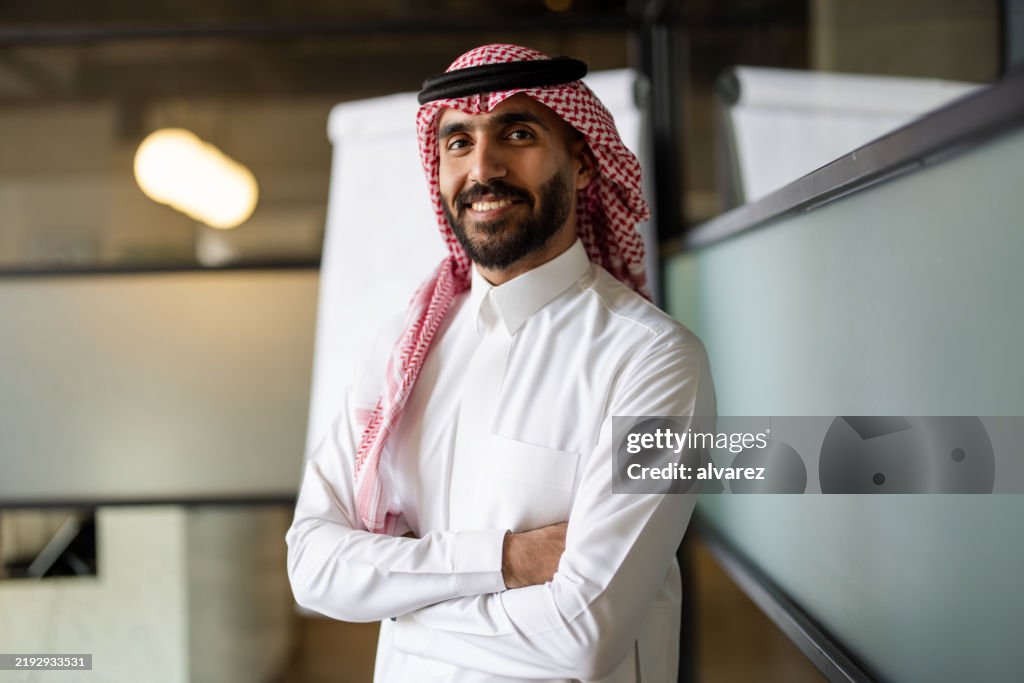 Middle Eastern male professional in traditional clothing standing in meeting room