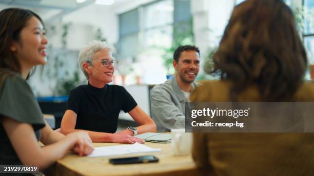 un equipo multirracial participa en un debate colaborativo en una oficina ecológica - empresa de carácter social fotografías e imágenes de stock