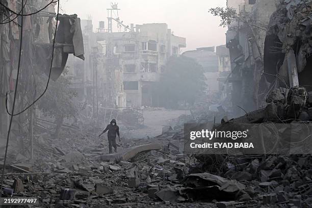Man walks through the rubble of buildings destroyed in Israeli airstrikes at the Bureij camp for Palestinian refugees in the central Gaza Strip on...
