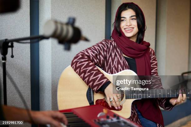 gitarre spielend und singend nimmt eine frau musik in einem professionellen tonstudio auf. - musikzubehör stock-fotos und bilder