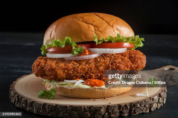 a fried cutlet burger on a wooden board - chicken burger stock pictures, royalty-free photos & images