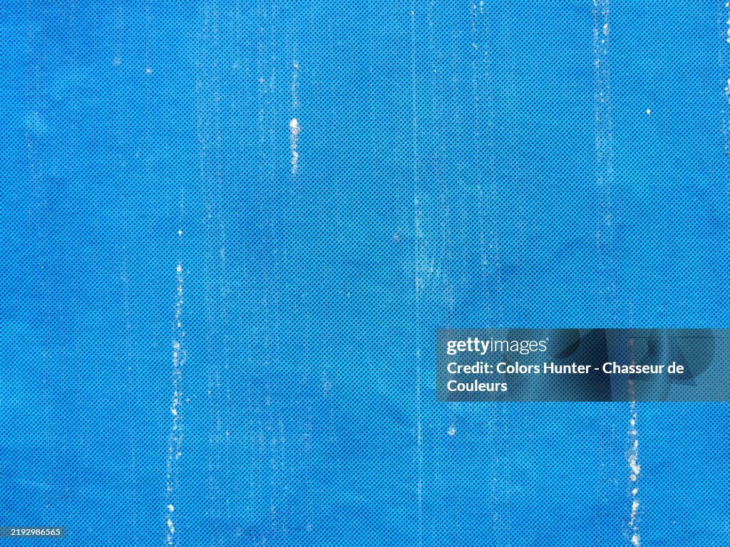 A weathered and scratched blue paper with black dots. Rough texture.
