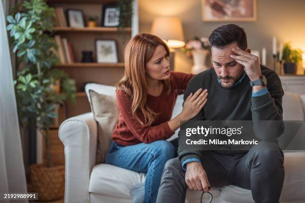a woman comforts her depressed partner - husband stock pictures, royalty-free photos & images