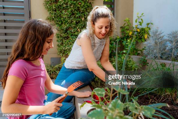 mère et fille jardinant ensemble dans un cadre extérieur ensoleillé - main verte photos et images de collection