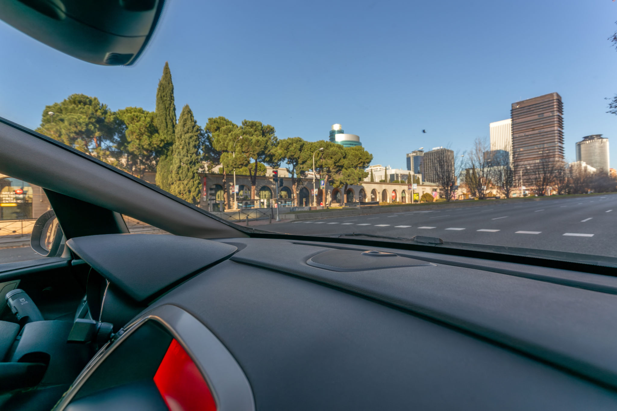View from inside a vehicle driving along Paseo de la Castellana near Nuevos Ministerios on a sunny morning. View from inside a vehicle driving along Paseo de la Castellana near Nuevos Ministerios on a sunny morning.