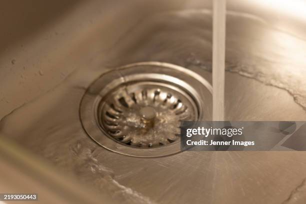 close-up of a plug hole a kitchen sink with water pouring. - abfluss stock-fotos und bilder