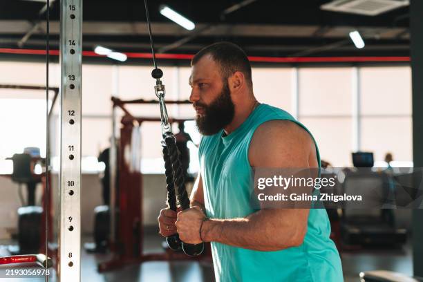 young man doing strength training with barbell in the gym - powerlifting stock pictures, royalty-free photos & images