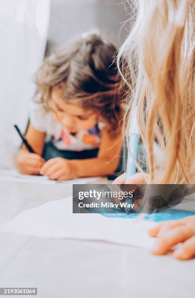 siblings girls lying on floor and drawing with color felt pens. - ausmalen stock-fotos und bilder