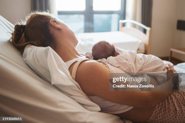 mother cradles newborn in hospital room during peaceful moment - newborn stock pictures, royalty-free photos & images