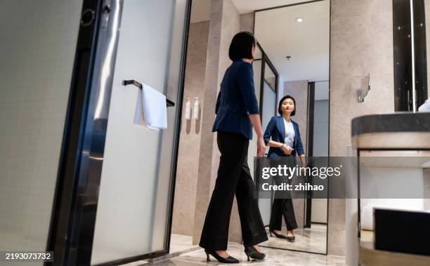 young woman walks out of the bathroom - woman-looking-into-mirror-full-body stock pictures, royalty-free photos & images