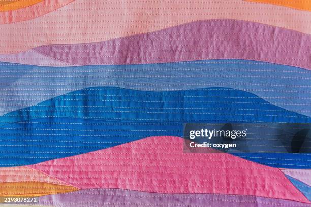 close-up of vibrant fabric pattern with stitching. detailed view of a colorful, textured fabric design featuring wavy patterns and visible stitching, showcasing creativity and craftsmanship. - trabalho à base de remendos imagens e fotografias de stock