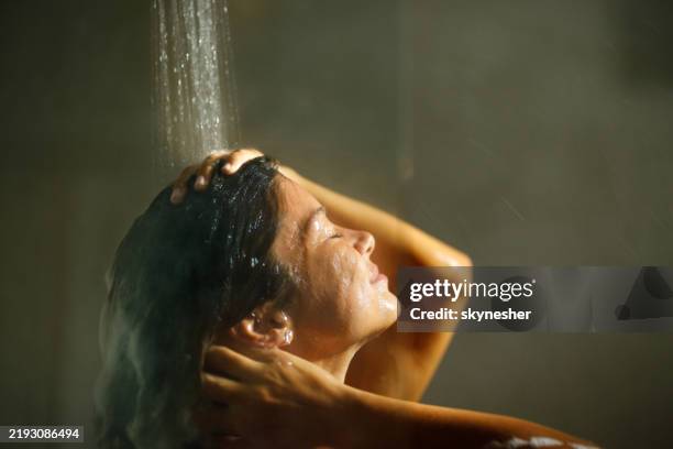 woman enjoying while washing hair with her eyes closed. - washing hair stock pictures, royalty-free photos & images