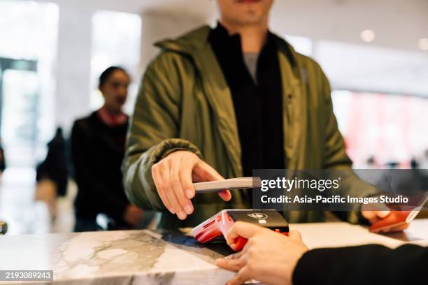 close up of asian businessman using smartphone for contactless payment at hotel reception. smartphone contactless payment concept. - digital wallet stock pictures, royalty-free photos & images