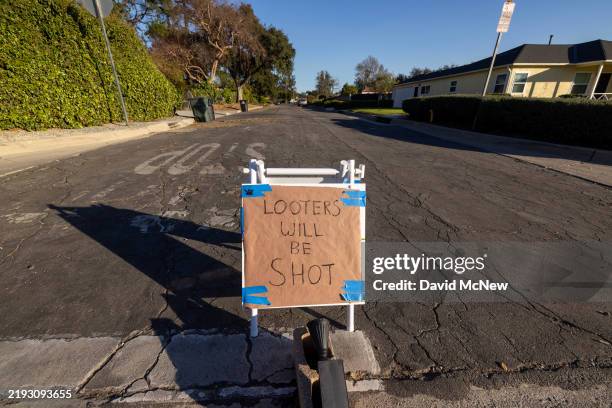 Sign reading 'Looters will be shot' stands in a mandatory evacuation zone at the Eaton Fire on January 12, 2025 in Altadena, California. The death...