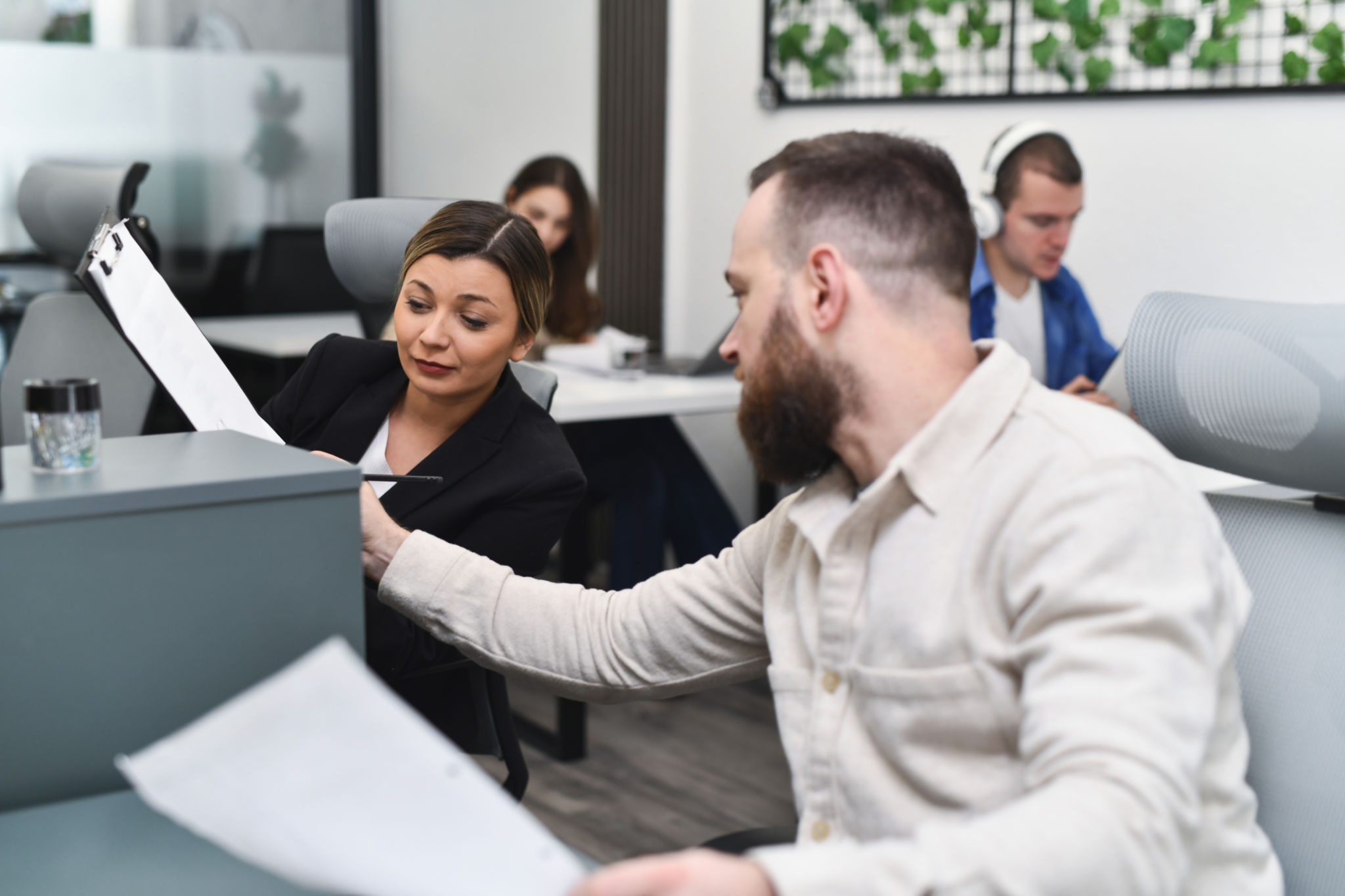 Male Helping Female Colleague Examining Her Notes Making Sure Everything's Correct Male Helping Female Colleague Examining Her Notes Making Sure Everything's Correct