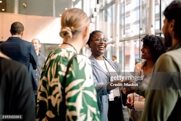 happy business professionals laughing while interacting with each other during seminar at convention center - reunião encontro social imagens e fotografias de stock