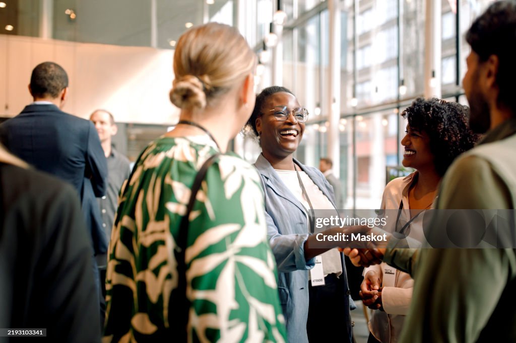 Happy business professionals laughing while interacting with each other during seminar at convention center