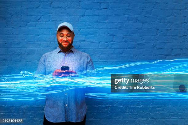 man using smart phone infront of blue wall with light trail - blockchain stock pictures, royalty-free photos & images