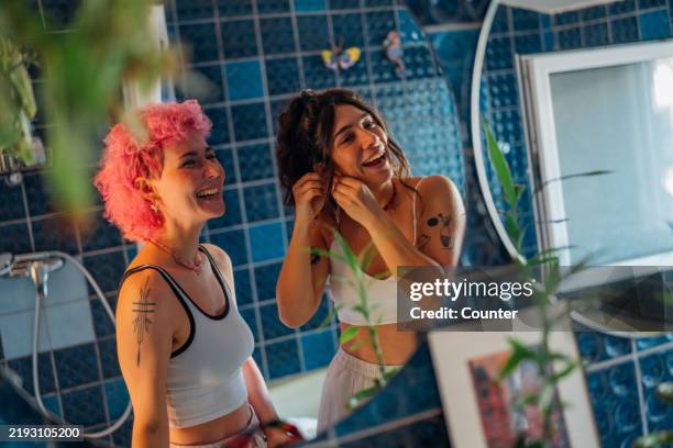 friends putting on jewellery in front of bathroom mirror - friends no makeup stock pictures, royalty-free photos & images
