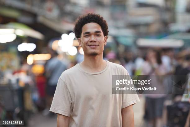 curly haired young man with smirking face - sourire narquois photos et images de collection
