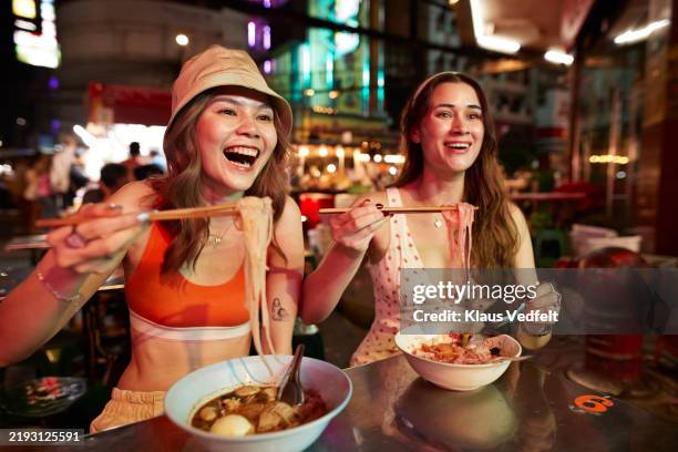 happy friends eating ramen noodles with chopsticks - eating ramen noodles stock pictures, royalty-free photos & images