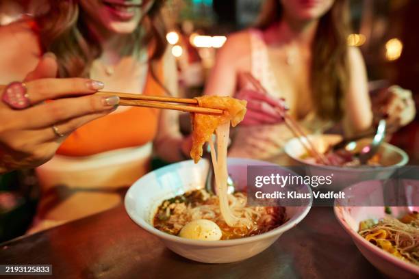 hand of woman holding noodles with chopsticks - streetfood stock-fotos und bilder