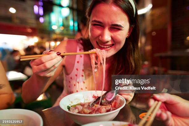 portrait of smiling young woman eating noodles - chopsticks stock pictures, royalty-free photos & images