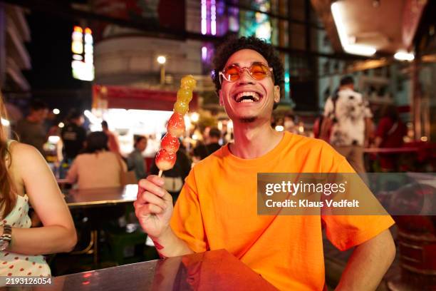 young man holding strawberry stick - turismo esperienziale foto e immagini stock