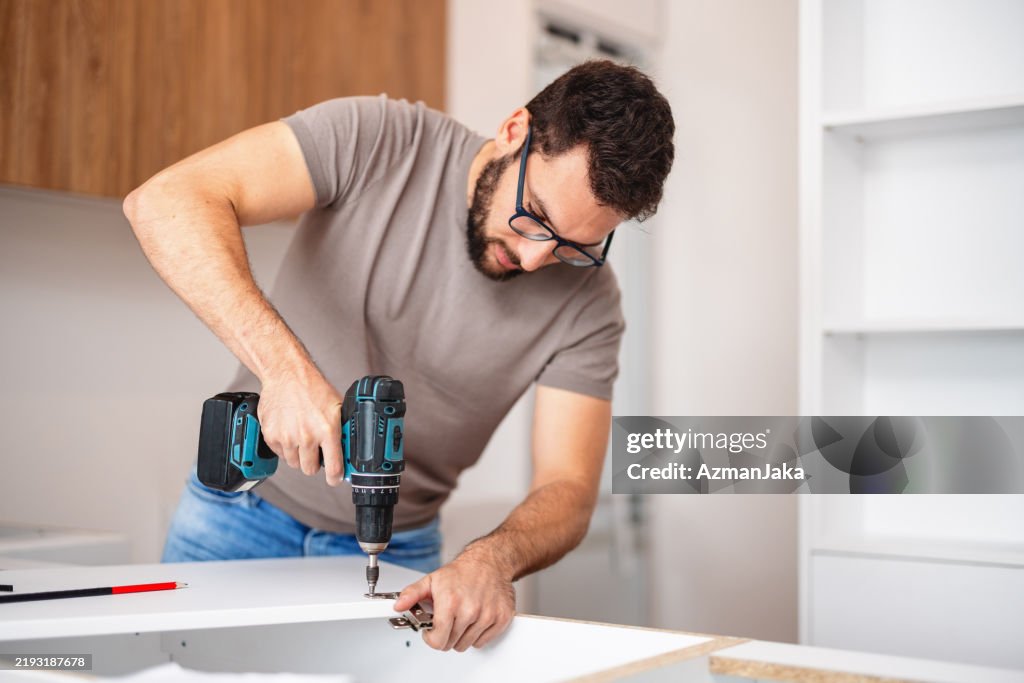 Carpenter Fitting New Kitchen Cabinet in Modern Apartment