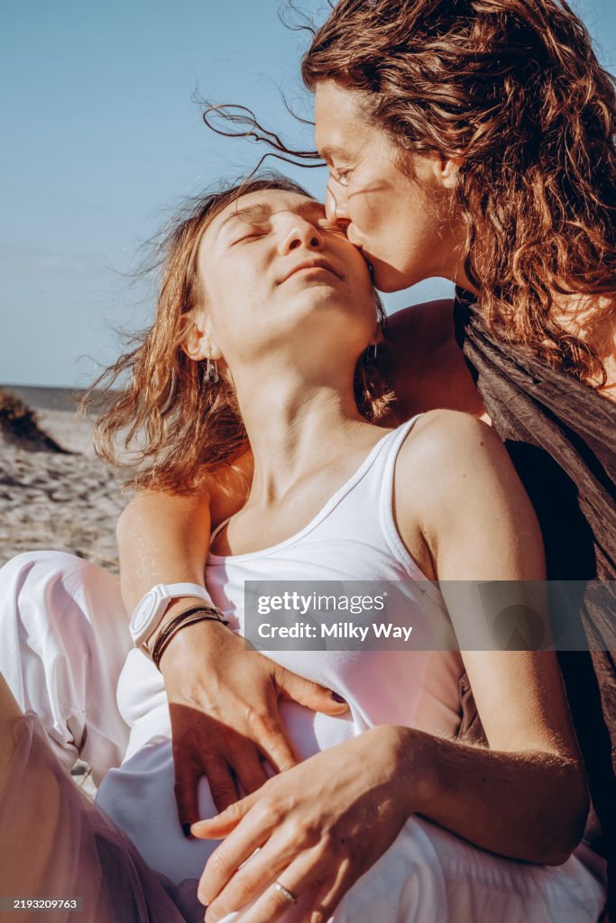 Romantic moment: couple sharing an intimate kissing by the sea. Romantic lesbian kiss on the beach.