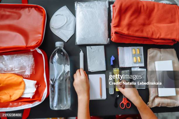 close-up of a woman's hands packing a flashlight in a doomsday prep kit on the table at home. - kit-de-primeiros-socorros imagens e fotografias de stock