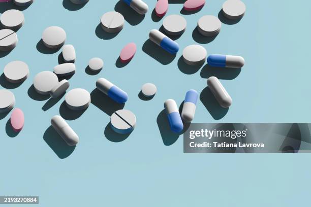 many pharmaceutical capsules and tablets scattered on a pastel colored blue background with copy space. healthcare, medical treatment concept - bescherming tegen corona stockfoto's en -beelden