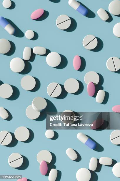 many pharmaceutical capsules and tablets scattered on a pastel colored blue background with copy space. healthcare, medical treatment concept - bescherming tegen corona stockfoto's en -beelden