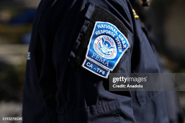 Federal Emergency Management Agency officer is seen as Cal Fire search and rescue team look through with a rescue dog for possible human remains in...