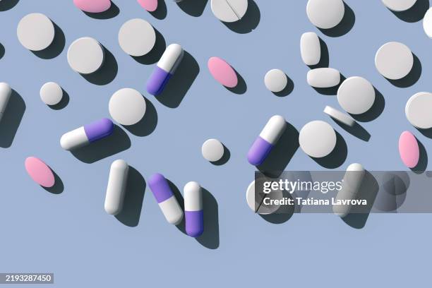many pharmaceutical capsules and tablets scattered on a pastel colored blue background with copy space. healthcare, medical treatment concept - bescherming tegen corona stockfoto's en -beelden