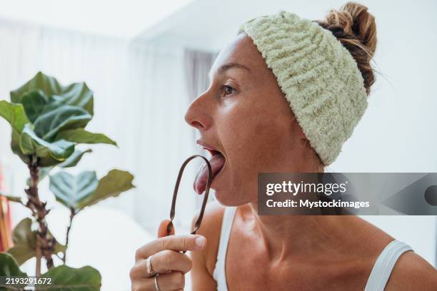 woman practicing tongue cleaning in modern bathroom - tongue scraper stock pictures, royalty-free photos & images