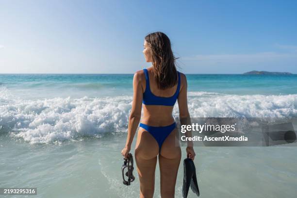una mujer joven se adentra en el mar con equipo de snorkel - biquini fotografías e imágenes de stock
